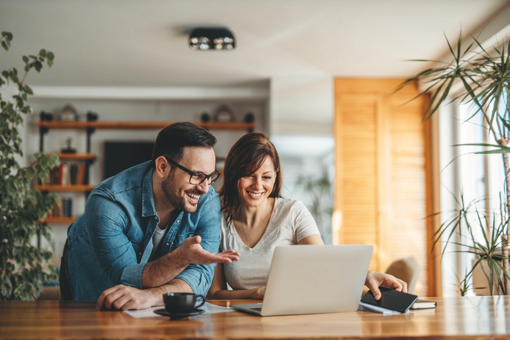 casal sorrindo e olhando para um notebook - energia solar
